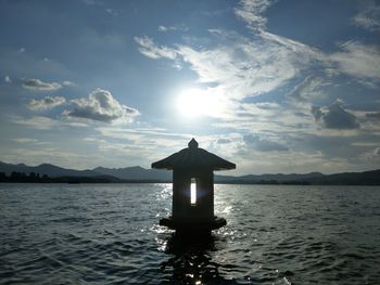 Silhouette cross on sea against sky