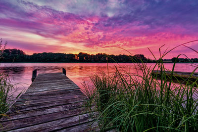 Pier over lake against sky during sunset