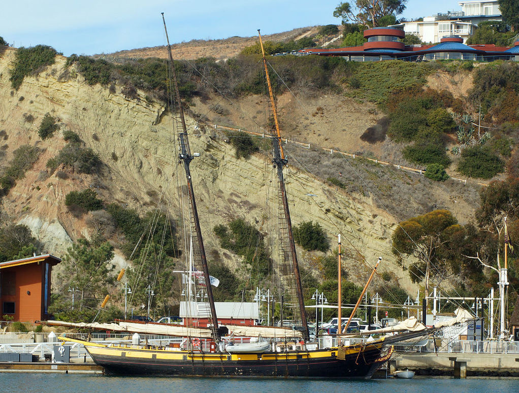 BOATS MOORED IN RIVER AGAINST MOUNTAIN