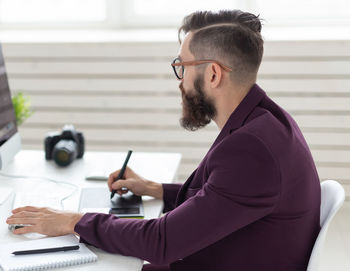 Young man using mobile phone while sitting on table