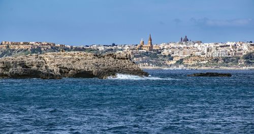 Sea by buildings against sky