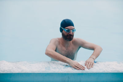 Rear view of shirtless boy swimming in pool