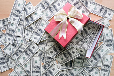 High angle view of gift box with paper currencies on table