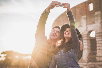 Cheerful couple taking selfie while standing outdoors