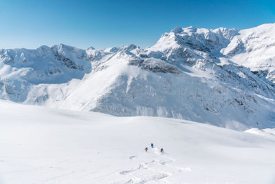 Group of people skiing in fresh powder snow in vast alpine landscape, gastein, austria.