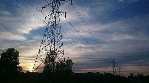 Low angle view of electricity pylon against cloudy sky