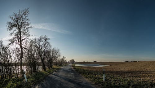 Road amidst field against sky