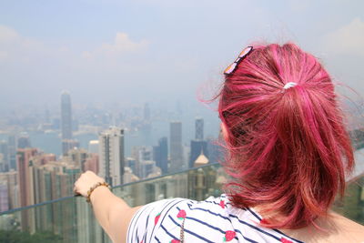 Rear view of woman with umbrella against cityscape