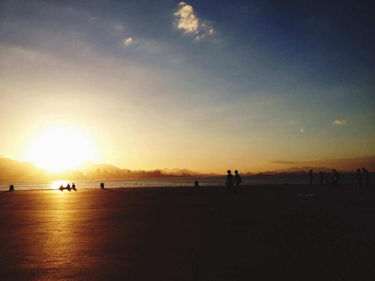 sunset, silhouette, sea, sun, water, sky, orange color, scenics, horizon over water, beauty in nature, beach, large group of people, tranquil scene, tranquility, leisure activity, lifestyles, medium group of people, nature, sunlight