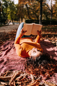 Midsection of man reading book on field