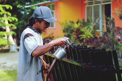 Side view of young man holding hat