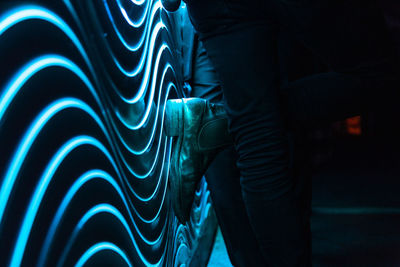 Midsection of man standing against illuminated wall at night