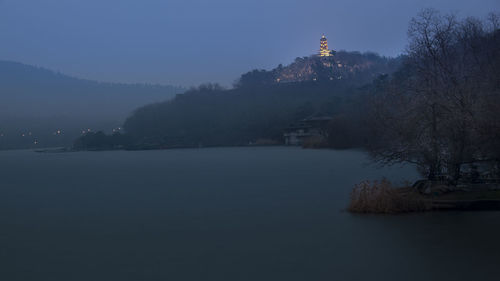 Scenic view of lake by building against sky during winter