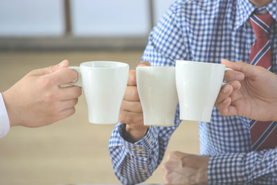 Midsection of man holding coffee cup