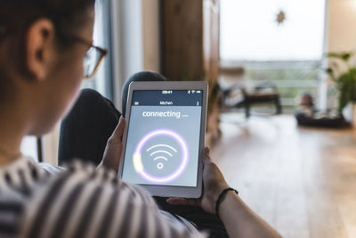 Woman using tablet with wifi symbol at home