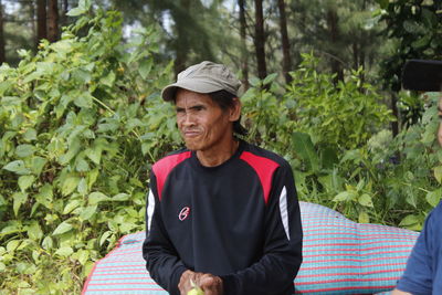 Mid adult man standing by trees against plants