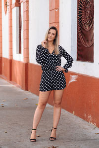 Full length portrait of woman standing on footpath