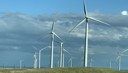 Windmills on field against sky