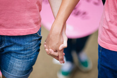Midsection of man and woman holding hands outdoors