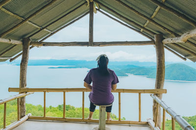 Rear view of woman standing on railing against sky