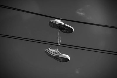 Old pair of converse shoes hanging from a wire in black and white