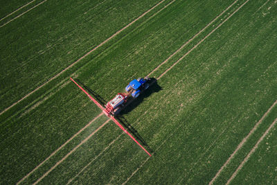 Tractor spraying fertilizer on green crop field, aerial view