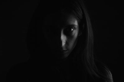 Close-up portrait of a young woman against black background