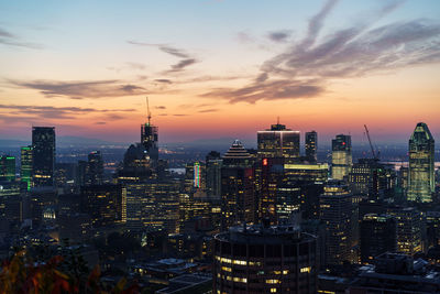 Illuminated cityscape against sky at sunset