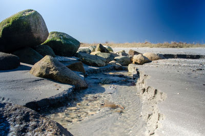 Rocks on beach against clear blue sky