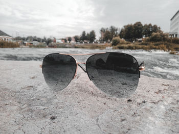 Close-up of sunglasses on beach against sky