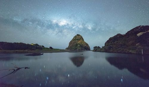 Rocks in sea against sky at night