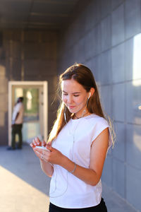 Portrait of young woman standing against wall