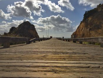 Surface level of wooden bridge against sky