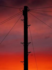 Low angle view of silhouette electricity pylon against sky during sunset