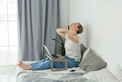 Full length of woman with arms raised on bed at home