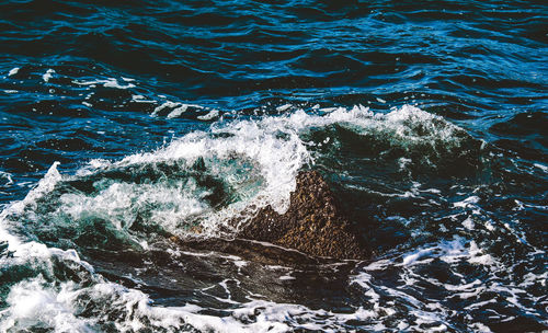 High angle view of sea waves splashing on rocks