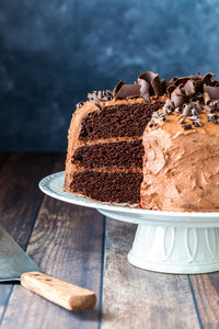 A triple layered decadent low sugar chocolate cake with one slice removed.