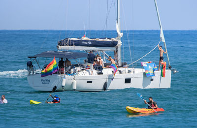 People on sailboat in sea against sky