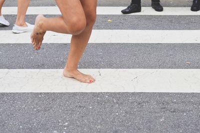 Low section of woman crossing road