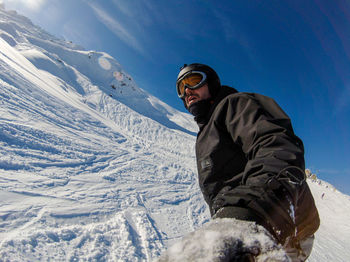 Low angle view of man standing on snow covered mountain against sky