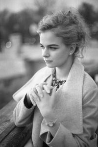 Young woman looking away while sitting outdoors