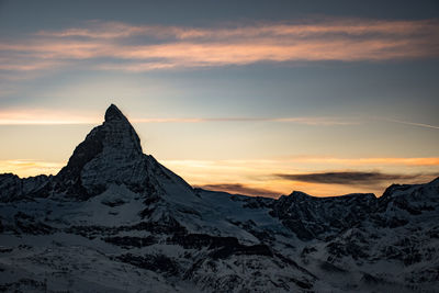 Scenic view of snowcapped mountains against sky at sunset