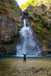 Man standing on rock against waterfall