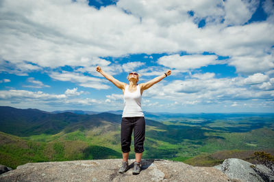 Full length of woman standing on rock against sky