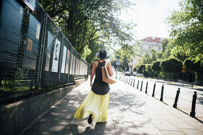 Rear view of woman standing on footpath