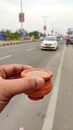 Close-up of hand holding car on road