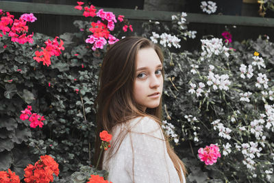 Portrait of young woman standing by flowering plants