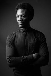 Portrait of young man standing against gray background