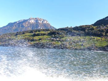 Scenic view of lake and mountains against clear blue sky