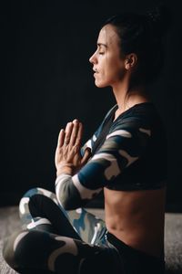 Side view of woman doing yoga while sitting at home